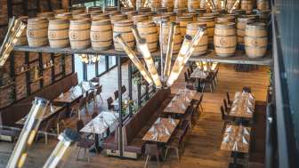 Einladender Brauereiraum mit langen Holztischen, Fass-Dekorationen und stilvoller Beleuchtung