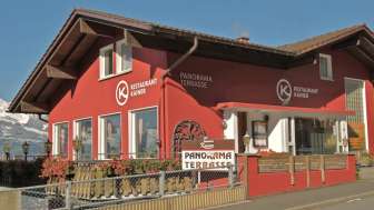 Rotes Gebäude des Restaurant Kainer mit Holzbalkon und einladendem Aussenbereich