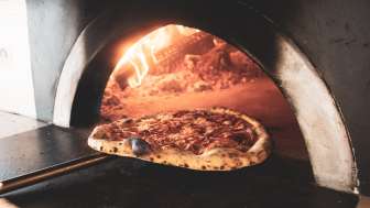 Pizza im Holzofen mit goldbraunem Rand und knuspriger Kruste