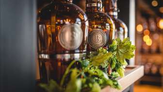 Flaschen mit frisch gezapftem Bier auf sonnendurchfluteter Terrasse, umgeben von lebendiger Stimmung