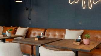 Ein modernes Café mit Ledersofas, hellen Sesseln und Holztischen