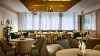 Ein weiterer Winkel des Essbereichs, mit den gleichen runden Tischen, einer gemütlichen Atmosphäre und modernen Lichtinstallationen.