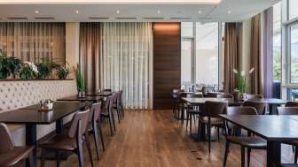 Modern eingerichtetes Restaurant Kommod mit dunklem Holzinterieur und gepolsterten Sitzbänken