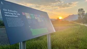 Infotafel zum Ernährungsfeld Vaduz mit Blick auf die Alpen im Sonnenuntergang – ein Lernort zur nachhaltigen Ernährung in Liechtenstein.