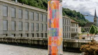 Farbenfrohe Jubiläumsstele in Vaduz mit leuchtenden Ornamenten, gestaltet von Künstlerin Evelyne Bermann.