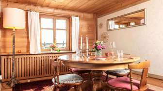 Gemütlicher Speiseraum mit Holztäfelung, rundem Esstisch und rustikalem Interieur