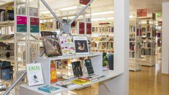 Heller Eingangsbereich der Liechtensteinischen Landesbibliothek mit modernen Bücherregalen und Ausstellungsfläche für Neuerscheinungen