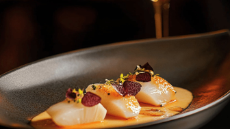 Kunstvoll angerichtetes Gericht auf schwarzem Teller