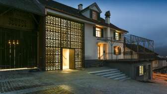 Modern beleuchtetes Kulturhaus Rössle in Mauren bei Abenddämmerung, mit Glasfassade, historischem Gebäudeanbau und gepflastertem Vorplatz.