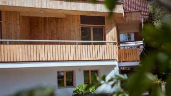 Außenansicht des Gästehauses beim Camping Mittagsspitze mit Holzfassade und Balkon in naturnaher Umgebung