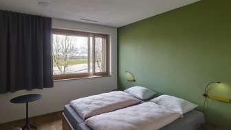 Zweibettzimmer mit grün gestrichener Wand in der Jugendherberge Schaan-Vaduz