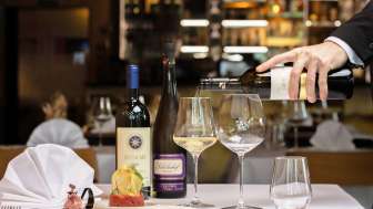 Kellner schenkt Weißwein zu einem elegant angerichteten Tellergericht im Restaurant Alpspitz ein.