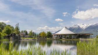 Moderner Pavillon am Wasser in der Freizeitanlage Grossabünt in Liechtenstein, umgeben von Natur und mit Blick auf die Alpen.