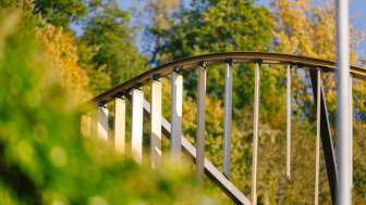 Nahaufnahme des gewölbten Metallbogens mit vertikalen Lamellen des Centrum für Kunst vor herbstlicher Waldkulisse in Vaduz.