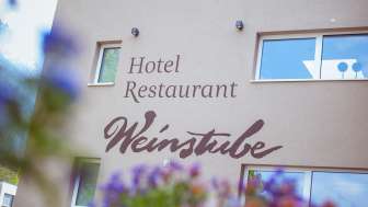 Aussenansicht des Restaurant Weinstube mit Blumen im Vordergrund