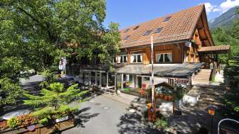 Außenansicht des Haupthauses des Campingplatzes Mittagsspitze mit Restaurant und schattiger Terrasse.