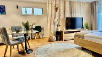 Stilvoll eingerichtetes Studio mit Kingsize-Bett, Flachbild-TV und Tisch mit zwei Stühlen