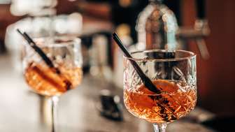 Zwei Aperitif-Gläser mit Orangenscheiben auf der Bar