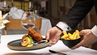 Serviertes Gericht mit paniertem Fleisch und Pommes Frites in moderner Präsentation im Restaurant Alpspitz.