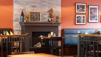 Gemütlicher Gastraum im Restaurant new castle mit warmen Farben, Kamin und stilvollen Holztischen