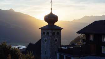 Zwiebelturm der Pfarrkirche St. Josef mit untergehender Sonne im Hintergrund