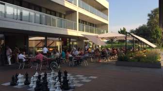 Gut besuchte Sonnenterrasse eines modernen Restaurants mit Grossschachfeld im Aussenbereich