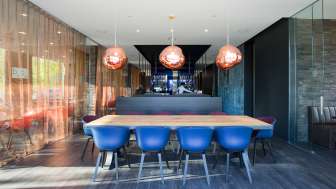 Modernes Restaurant mit stilvollem Interieur, blauen Designerstühlen und eleganter Bar im b_smart Hotel